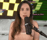 a woman stands in front of a microphone in front of a screen that says ' chris ' on it