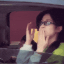 a woman wearing glasses is looking out of a car window