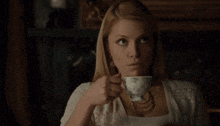 a man is drinking a cup of tea in a dark room