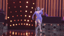 a man and a woman are dancing on a stage with an orchestra behind them
