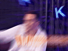 a blurry picture of a man covering his face in front of a sign that says k