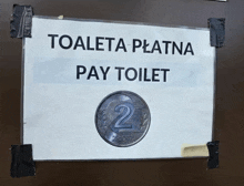 a sign that says toaleta platna pay toilet is taped to a wall