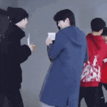 a man in a blue coat is standing next to another man in a red hoodie