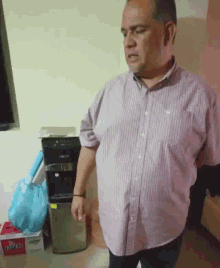 a man in a pink striped shirt is standing in front of a box of pepsi