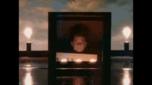 there is a picture of a man in a frame with candles in the background .