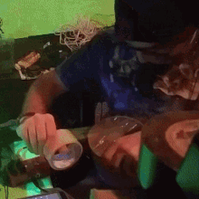 a man in a blue shirt is holding a cup in front of his face