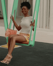 a woman sitting on a green swing with a pink purse