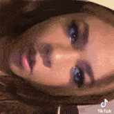 a close up of a woman 's face with a tiktok logo