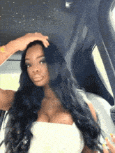 a woman with long black hair is sitting in a car with her hand on her head