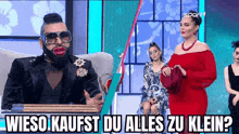 a man with a beard and sunglasses is sitting in front of a woman in a red dress .