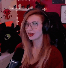 a woman wearing glasses and headphones is sitting in front of a microphone in a room .