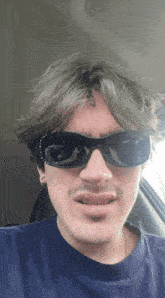a man wearing sunglasses and a blue shirt is making a face
