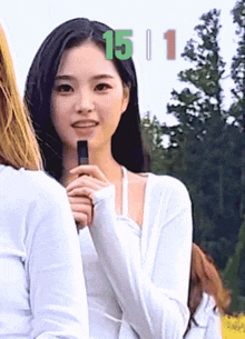 a woman in a white shirt holds a microphone in front of the number 15 and 1