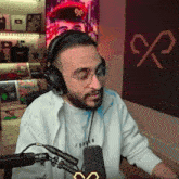 a man is wearing headphones and glasses while sitting in front of a microphone .