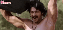 a shirtless man with a mustache is holding a rock in his hands .