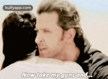 a man is hugging another man and says `` now take my guns and ... ''