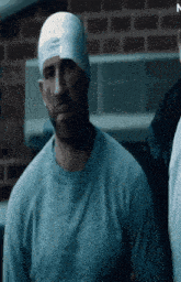 a man with a bandage on his head is wearing a grey shirt