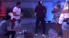 a group of people are dancing in a room with a fan and a clock that says 12