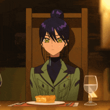 a woman in a green jacket sits at a table with a plate of food