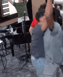 a group of people are dancing in a room in front of a piano and a microphone .
