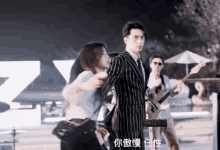 a man in a striped suit is dancing with a woman while a man plays a guitar .