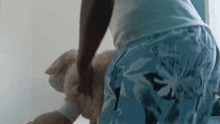 a man in blue shorts is kneeling down next to a dog .