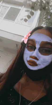 a girl wearing a mask with a pink flower in her hair