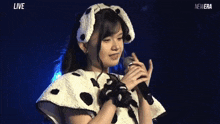 a girl in a dalmatian costume sings into a microphone