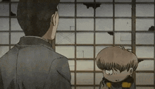 a man and a little boy are standing next to each other in front of a window .