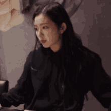 a woman with long black hair is wearing a black sweatshirt