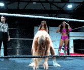 three women are wrestling in a ring with one wearing a pink outfit
