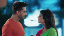 a man and a woman are looking at each other . the woman is wearing a green dress .