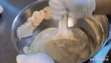 a person is mixing a batter in a metal bowl .