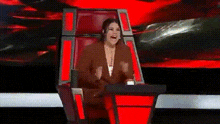 a woman is sitting in a chair on a stage with her mouth open .