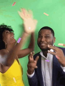 a woman in a yellow dress and a man in a suit are giving each other high fives