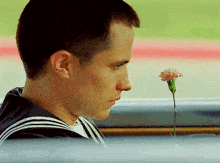 a man in a sailor suit smells a flower