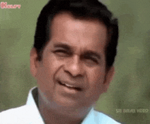 a man is smiling and making a funny face while wearing a white shirt .