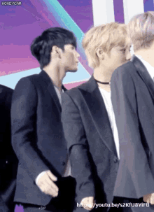 a man in a suit stands next to another man in a suit