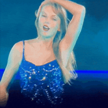 a woman in a blue sequined top is dancing on a stage