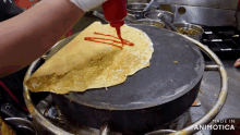 a person is pouring ketchup on a tortilla that is being made in animatica