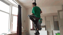 a man in a green shirt is doing a trick in a room with a mirror