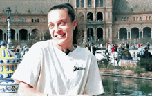 a woman wearing a t-shirt that says supreme smiles in front of a large building