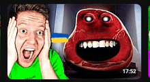a man in a green shirt is standing in front of a red monster with a big mouth .