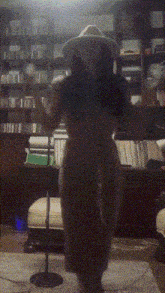 a naked woman wearing a hat is standing in front of a microphone