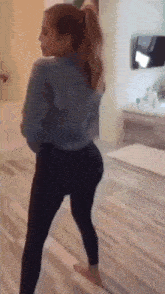 a woman in a denim jacket and black leggings is dancing in a room .