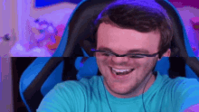 a man wearing glasses and headphones is sitting in a blue chair .
