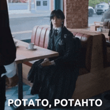 a woman in a black dress is sitting at a table with the words potato potahto written below her