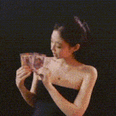 a woman in a black dress is holding two cards in her hands in front of a black background .