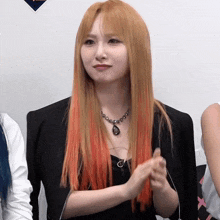 a woman with long blonde hair is wearing a black jacket and a black necklace