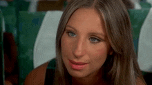 a woman with long hair and blue eyes is sitting on an airplane and smiling .